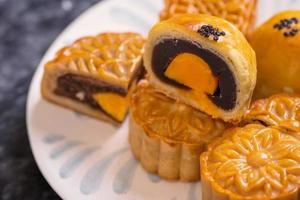 Tasty baked egg yolk pastry moon cake for Mid-Autumn Festival on black slate dark background. Chinese festive food concept, close up, copy space. photo