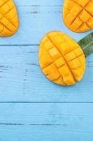 Fresh mango, beautiful chopped fruit with green leaves on dark wooden table background. Tropical fruit design concept. Flat lay. Top view. Copy space photo