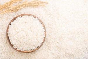 Raw white polished milled edible rice crop on white background in brown bowl, organic agriculture design concept. Staple food of Asia, close up. photo