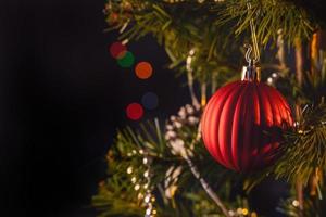 Beautiful Christmas decor concept, bauble hanging on the Christmas tree with sparkling light spot, blurry dark black background, macro detail, close up. photo