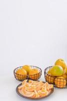 hermosas mandarinas peladas en un plato y una cesta de metal aisladas en una mesa limpia y blanca brillante en una moderna isla de cocina contemporánea, de cerca.