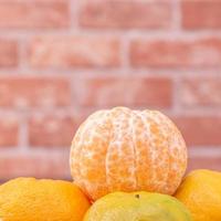 Peeled tangerines in a bamboo sieve basket on dark wooden table with red brick wall background, Chinese lunar new year fruit design concept, close up. photo