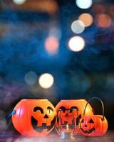 concepto de halloween - linterna de calabaza de plástico naranja sobre una mesa de madera oscura con una luz brillante borrosa en el fondo, truco o trato, de cerca. foto