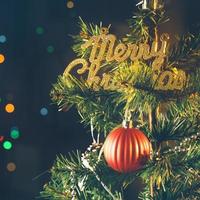 bello concepto de decoración navideña, adorno colgado en el árbol de navidad con punto de luz brillante, fondo negro oscuro borroso, detalle macro, primer plano. foto