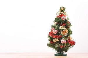 Decorated cute Christmas tree on a wooden floor with white background and toys, blank for festive design concept, close up. photo