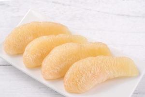 Fresh peeled pomelo, pummelo, grapefruit, shaddock on bright wooden table background. Seasonal fruit for Mid-Autumn Festival, close up, copy space. photo