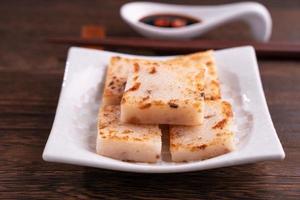 Delicious turnip cake, Chinese traditional local dish radish cake in restaurant with soy sauce and chopsticks, close up, copy space. photo