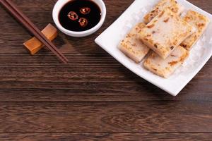 Delicious turnip cake, Chinese traditional local dish radish cake in restaurant with soy sauce and chopsticks, close up, copy space. photo