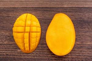 Fresh mango, beautiful chopped fruit with green leaves on dark wooden table background. Tropical fruit design concept. Flat lay. Top view. Copy space photo