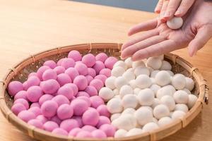 una mujer de asia está haciendo tang yuan, yuan xiao, albóndigas de arroz de comida tradicional china en rojo y blanco para el año nuevo lunar, festival de invierno, de cerca. foto