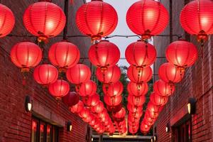 Beautiful round red lantern hanging on old traditional street, concept of Chinese lunar new year festival, close up. The undering word means blessing. photo