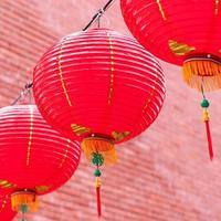 Beautiful round red lantern hanging on old traditional street, concept of Chinese lunar new year festival, close up. The undering word means blessing. photo