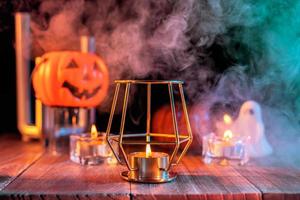 concepto de halloween, linterna de calabaza naranja y velas en una mesa de madera oscura con humo verde-naranja alrededor del fondo, truco o trato, cerrar foto