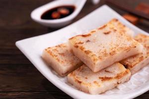 Delicious turnip cake, Chinese traditional local dish radish cake in restaurant with soy sauce and chopsticks, close up, copy space. photo