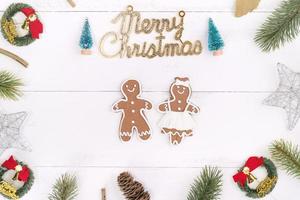 Christmas concept composition decoration objects, fir tree branch wreath, gingerbread man biscuit isolated on white wooden table, top view, flat lay photo