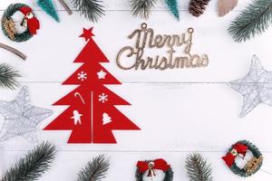 objetos de decoración de composición de concepto de navidad, corona de rama de abeto y adorno aislado en mesa de madera blanca, vista superior, plano, disposición. foto