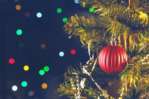 bello concepto de decoración navideña, adorno colgado en el árbol de navidad con punto de luz brillante, fondo negro oscuro borroso, detalle macro, primer plano. foto