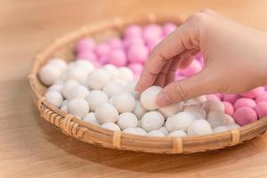 una mujer de asia está haciendo tang yuan, yuan xiao, albóndigas de arroz de comida tradicional china en rojo y blanco para el año nuevo lunar, festival de invierno, de cerca. foto