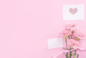 Beautiful, fresh elegant carnation flower bouquet with white greeting thanks gift card isolated on bright pink color background, top view, flat lay concept. photo
