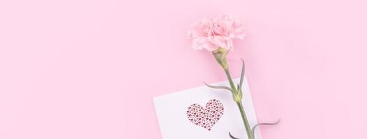 Beautiful, fresh elegant carnation flower bouquet with white greeting thanks gift card isolated on bright pink color background, top view, flat lay concept. photo