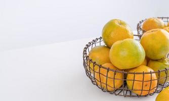 Beautiful peeled tangerines in a plate and metal basket isolated on bright white clean table in a modern contemporary kitchen island, close up. photo