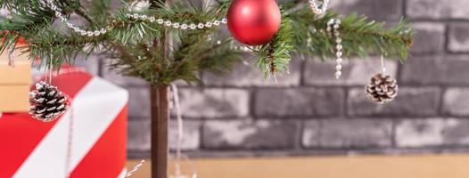 Decorated Christmas tree with wrapped beautiful red and white gifts at home with black brick wall, festive design concept, close up. photo