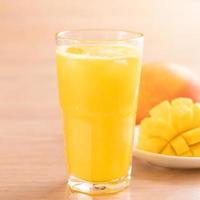 jugo de mango fresco con hermosa pulpa picada sobre fondo de mesa de madera brillante. concepto de diseño de bebidas de frutas tropicales. cerrar, copiar espacio. foto