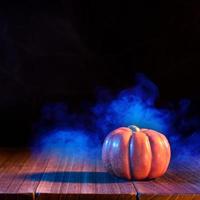 concepto de halloween - linterna de calabaza naranja sobre una mesa de madera oscura con humo de doble color alrededor del fondo, truco o trato, de cerca. foto