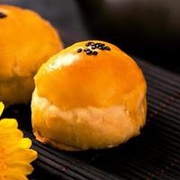 Tasty baked egg yolk pastry moon cake for Mid-Autumn Festival on black slate dark background. Chinese festive food concept, close up, copy space. photo