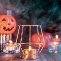concepto de halloween, linterna de calabaza naranja y velas en una mesa de madera oscura con humo verde-naranja alrededor del fondo, truco o trato, cerrar foto