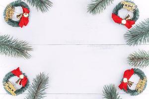 objetos de decoración de composición de concepto de navidad, corona de rama de abeto y adorno aislado en mesa de madera blanca, vista superior, plano, disposición. foto