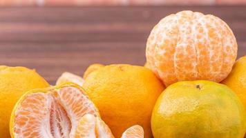 Peeled tangerines in a bamboo sieve basket on dark wooden table with red brick wall background, Chinese lunar new year fruit design concept, close up. photo