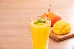 jugo de mango fresco con hermosa pulpa picada sobre fondo de mesa de madera brillante. concepto de diseño de bebidas de frutas tropicales. cerrar, copiar espacio. foto