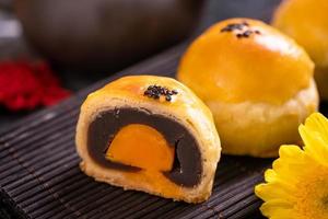 Tasty baked egg yolk pastry moon cake for Mid-Autumn Festival on black slate dark background. Chinese festive food concept, close up, copy space.
