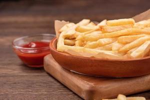 Golden yummy deep French fries on kraft baking sheet paper and serving tray to eat with ketchup and yellow mustard, close up, lifestyle. photo