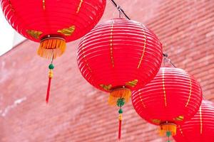 Beautiful round red lantern hanging on old traditional street, concept of Chinese lunar new year festival, close up. The undering word means blessing. photo