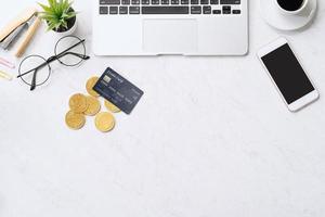 Concept of online payment with credit card with smart phone, laptop computer on office desk on clean bright marble table background, top view, flat lay photo