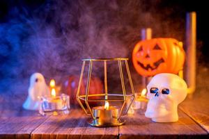 concepto de halloween, linterna de calabaza naranja y velas en una mesa de madera oscura con humo azul-naranja alrededor del fondo, truco o trato, cerrar