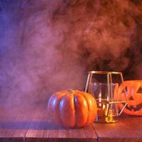 concepto de halloween, linterna de calabaza naranja y velas en una mesa de madera oscura con humo azul-naranja alrededor del fondo, truco o trato, cerrar foto