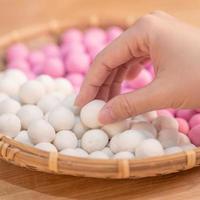An Asia woman is making Tang yuan, yuan xiao, Chinese traditional food rice dumplings in red and white for lunar new year, winter festival, close up. photo