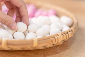 An Asia woman is making Tang yuan, yuan xiao, Chinese traditional food rice dumplings in red and white for lunar new year, winter festival, close up.