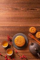 Chinese traditional pastry Moon cake Mooncake with tea cups on bamboo serving tray on wooden background for Mid-Autumn Festival, top view, flat lay. photo