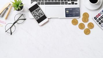 Online payment with QR code concept, virtual credit card, smart phone on office laptop desk on clean marble table background, top view, flat lay photo