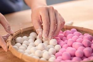 una mujer de asia está haciendo tang yuan, yuan xiao, albóndigas de arroz de comida tradicional china en rojo y blanco para el año nuevo lunar, festival de invierno, de cerca. foto