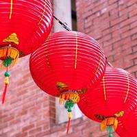Beautiful round red lantern hanging on old traditional street, concept of Chinese lunar new year festival, close up. The undering word means blessing. photo