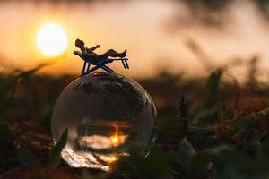 Miniature people sunbathing on crystal globe in The park photo