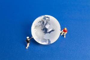 Miniature people Teenager spraying paint crytal globe on blue background photo