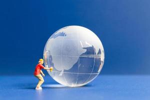 Miniature people Teenager spraying paint crytal globe on blue background photo