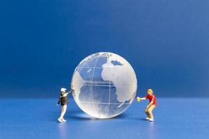 Miniature people Teenager spraying paint crytal globe on blue background photo