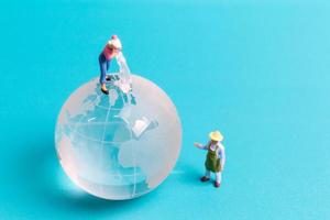 Miniature people cleaning crystal globe on blue background photo